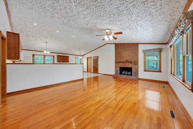 unfurnished living room with ceiling fan, a brick fireplace, light wood-type flooring, visible vents, and ornamental molding