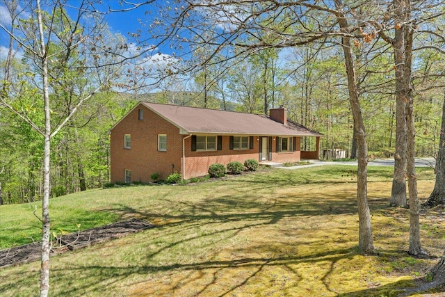 ranch-style house featuring brick siding, a chimney, and a front lawn