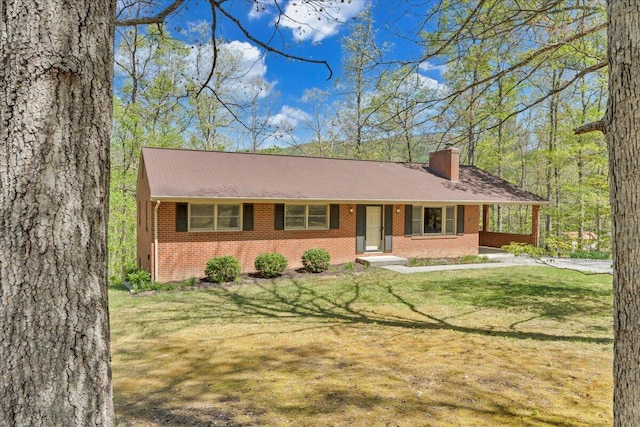 single story home featuring brick siding, a chimney, a shingled roof, and a front yard