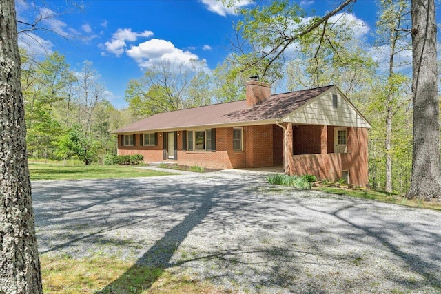 ranch-style house with brick siding, driveway, and a chimney