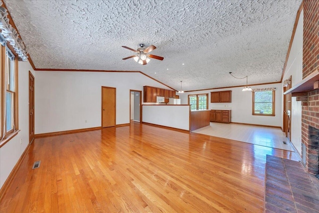 unfurnished living room with light wood finished floors, a brick fireplace, a textured ceiling, a ceiling fan, and visible vents