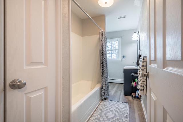 bathroom featuring wood finished floors, a baseboard heating unit, vanity, and shower / bath combo with shower curtain