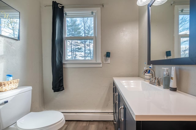 half bathroom featuring a baseboard radiator, healthy amount of natural light, toilet, and vanity