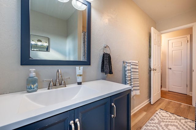 bathroom with wood finished floors, vanity, and baseboards