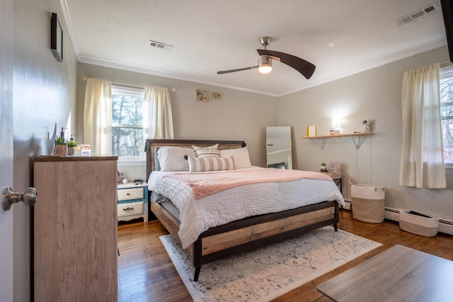 bedroom featuring crown molding, wood finished floors, ceiling fan, and a baseboard heating unit