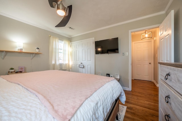 bedroom featuring wood finished floors, ornamental molding, a closet, a ceiling fan, and baseboards