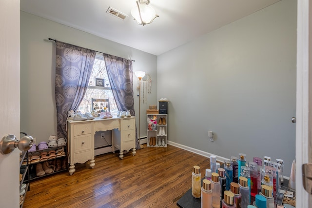 home office featuring a baseboard heating unit, wood finished floors, and baseboards