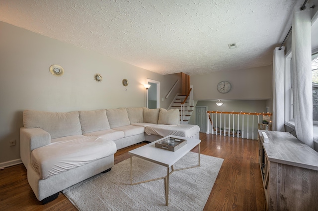 living area with a textured ceiling, dark wood-style flooring, and baseboards