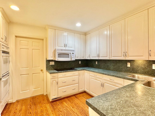 kitchen with white appliances, dark countertops, and light wood-style floors