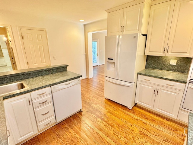 kitchen featuring dark countertops, white cabinets, light wood-type flooring, and white appliances