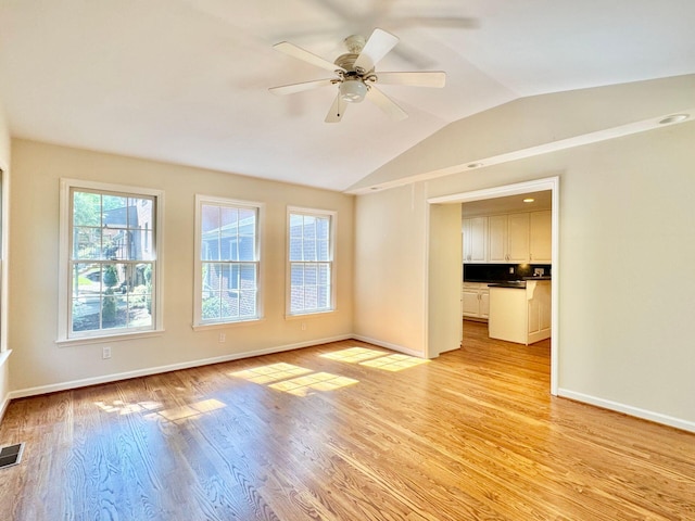 spare room featuring a ceiling fan, baseboards, lofted ceiling, light wood-type flooring, and visible vents