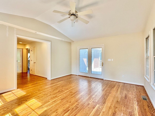 spare room featuring ceiling fan, visible vents, baseboards, lofted ceiling, and light wood-style floors