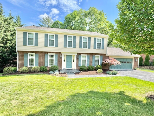 colonial home with brick siding, an attached garage, driveway, and a front yard