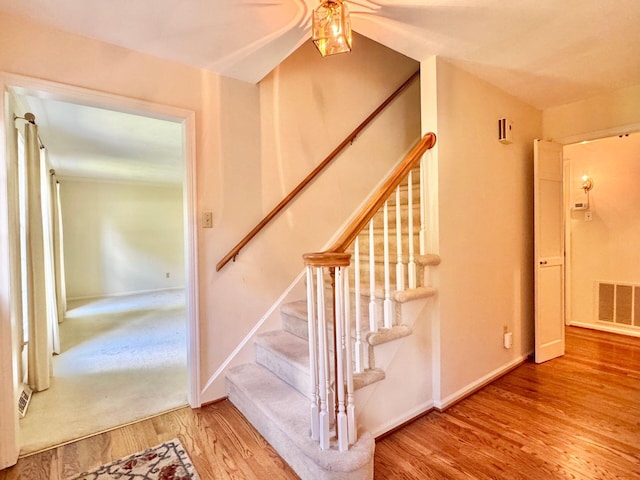 staircase featuring ceiling fan, baseboards, visible vents, and wood finished floors