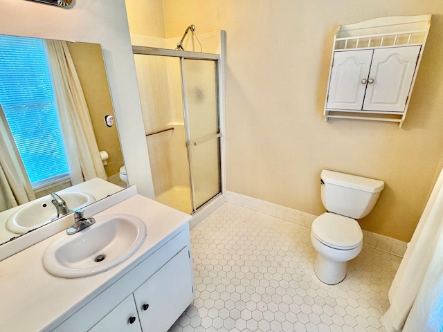 bathroom with vanity, baseboards, a shower stall, and toilet