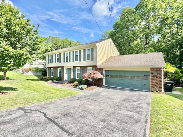 colonial house with brick siding, an attached garage, a front lawn, and aphalt driveway