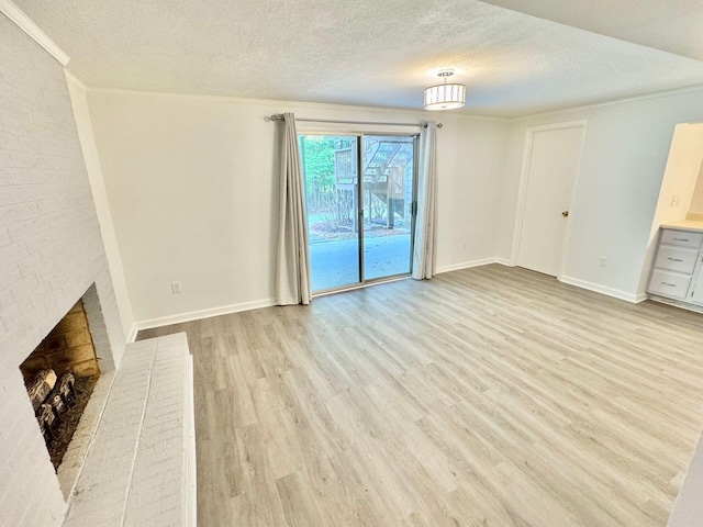 unfurnished living room with baseboards, a brick fireplace, light wood finished floors, and a textured ceiling