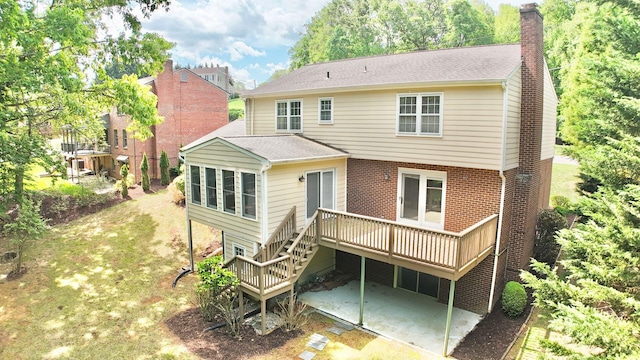 rear view of house with brick siding, a deck, a chimney, and a patio area