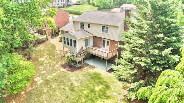 back of house with a chimney, a lawn, a deck, brick siding, and stairs