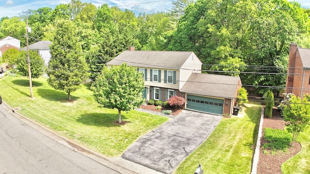 view of front of house featuring an attached garage, aphalt driveway, a front yard, and brick siding