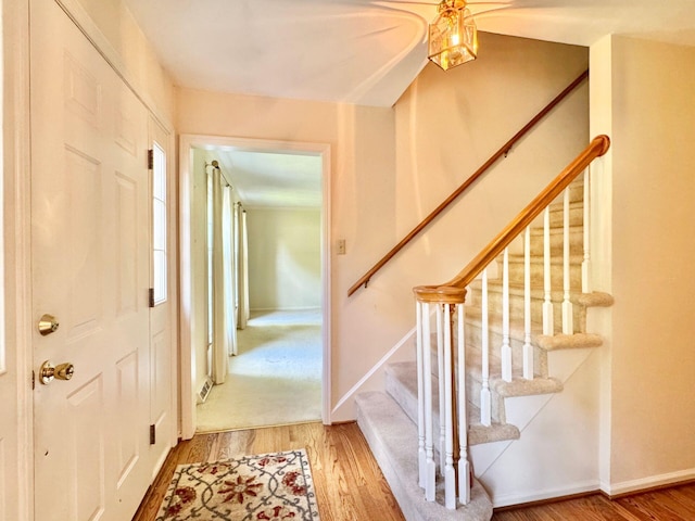 foyer featuring baseboards, stairs, and wood finished floors