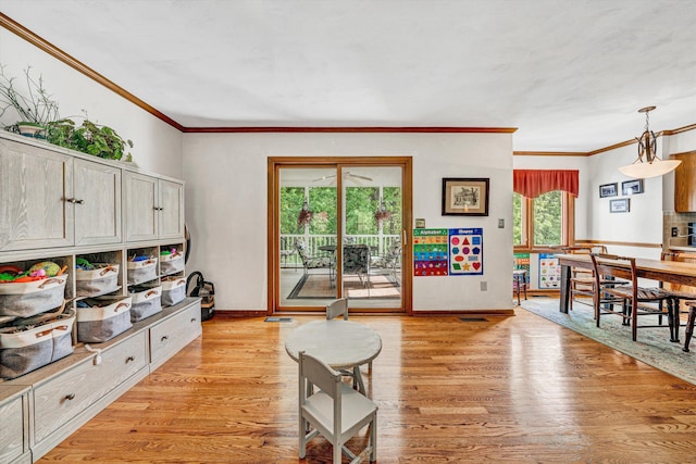 living area featuring crown molding, baseboards, and light wood-style flooring