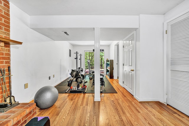 workout room featuring baseboards, visible vents, and light wood-style flooring