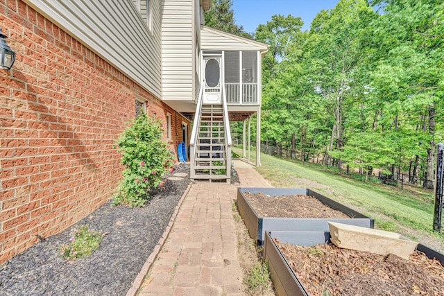 view of yard with a sunroom, a garden, fence, and stairway