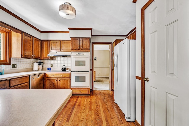 kitchen with brown cabinetry, white appliances, under cabinet range hood, tasteful backsplash, and light wood finished floors