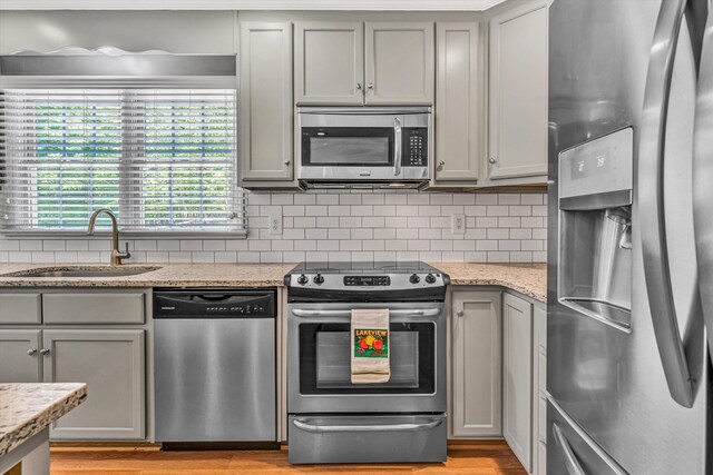 kitchen with gray cabinetry, appliances with stainless steel finishes, decorative backsplash, and a sink