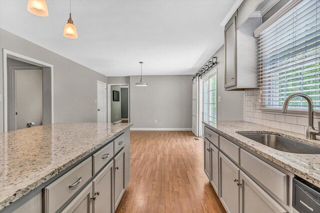 kitchen featuring a sink, baseboards, gray cabinetry, and light wood finished floors