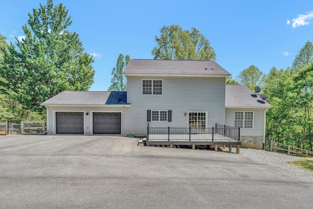 view of front facade with fence, an attached garage, a shingled roof, and aphalt driveway