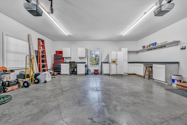 garage featuring a garage door opener and white refrigerator with ice dispenser