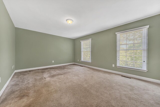 unfurnished room with baseboards, carpet floors, and visible vents