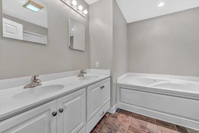 bathroom featuring double vanity, a sink, baseboards, and a bath