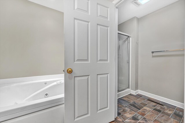 full bathroom with stone finish flooring, visible vents, a stall shower, a tub with jets, and baseboards
