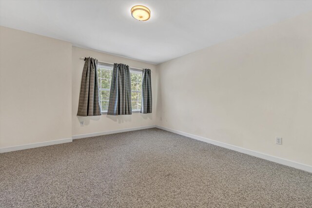 unfurnished room featuring carpet floors and baseboards