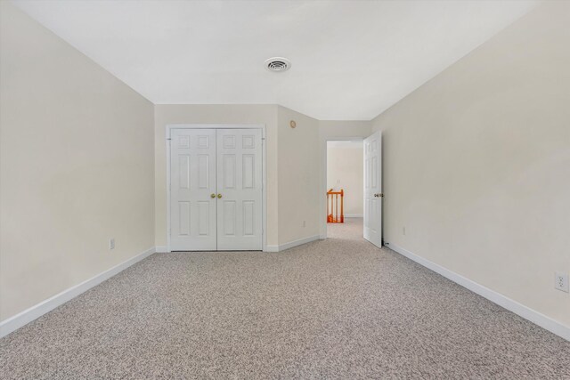unfurnished bedroom featuring a closet, baseboards, light colored carpet, and visible vents