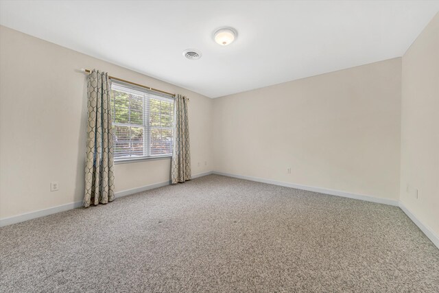 spare room with baseboards, carpet flooring, and visible vents
