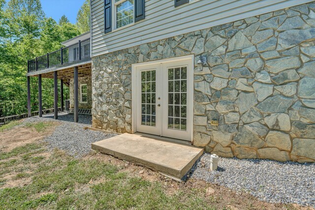 exterior space with a balcony, french doors, and stone siding