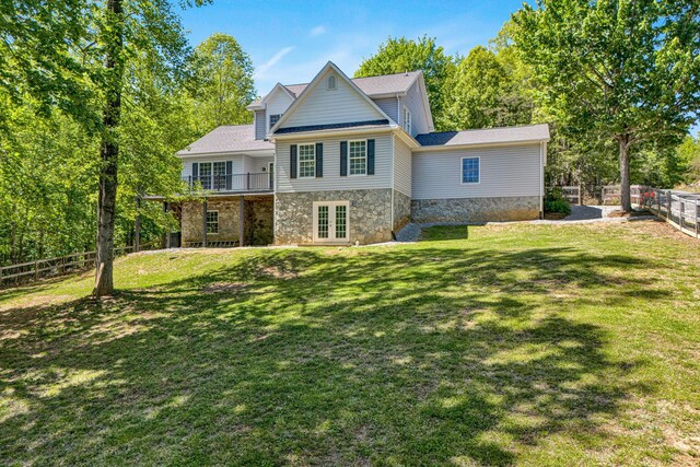 back of house featuring a fenced backyard, a yard, french doors, and stone siding