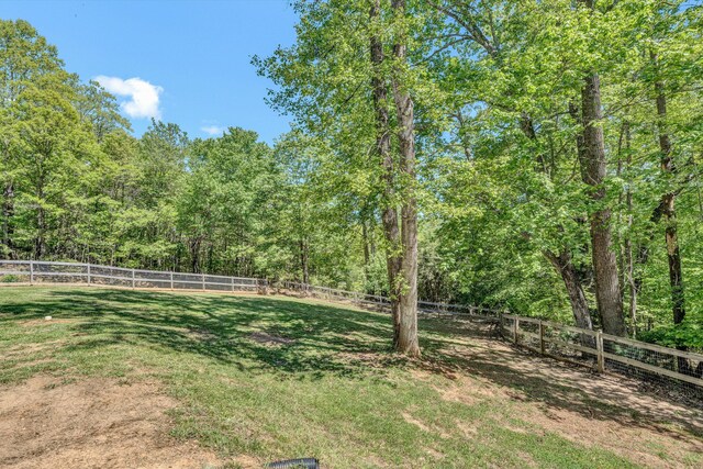 view of yard featuring a fenced backyard and a forest view