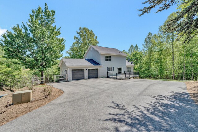 view of property exterior featuring an attached garage, a gate, and aphalt driveway