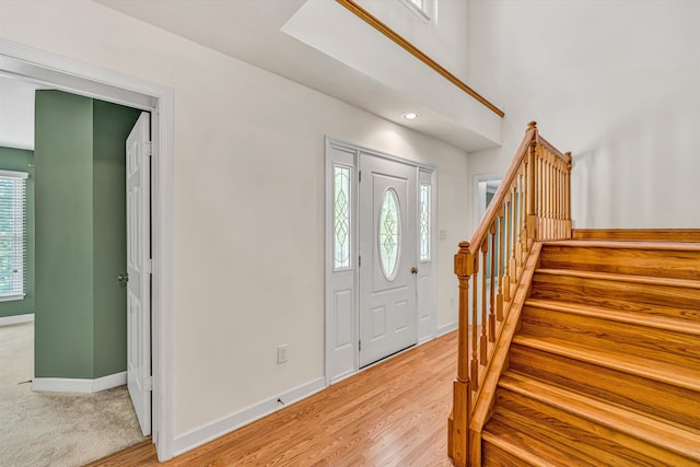 entrance foyer with baseboards, light wood-style flooring, a wealth of natural light, and stairway