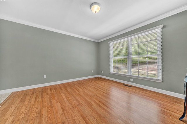 unfurnished room featuring baseboards, visible vents, ornamental molding, and wood finished floors