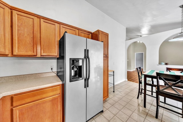 260 Harbor Landing Dr, Moneta, VA 24121 - kitchen with stainless steel fridge, arched walkways, light tile patterned flooring, brown cabinets, and light countertops