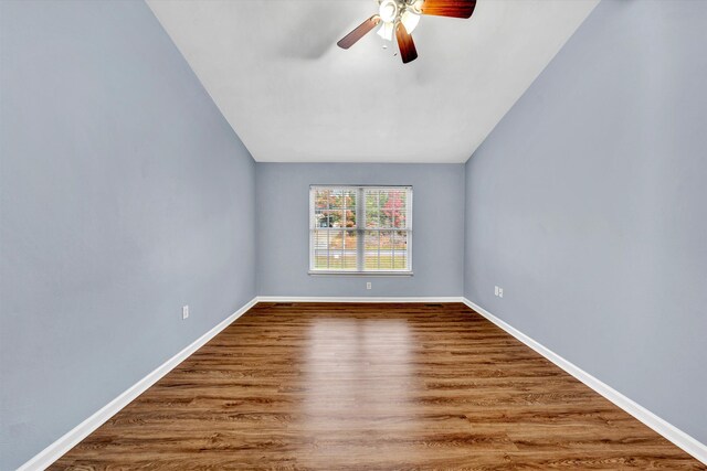 spare room with baseboards, ceiling fan, vaulted ceiling, and wood finished floors