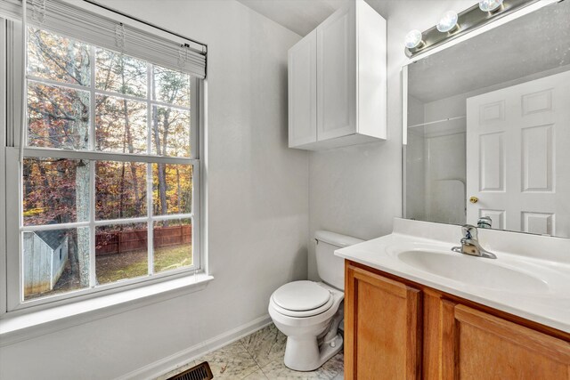 bathroom with toilet, baseboards, a wealth of natural light, and vanity