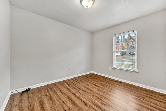 spare room with baseboards, wood finished floors, and visible vents