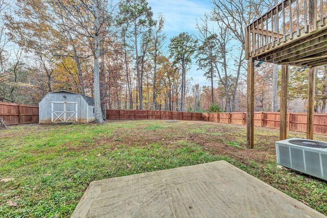 view of yard with a shed, a fenced backyard, an outbuilding, central AC unit, and a patio